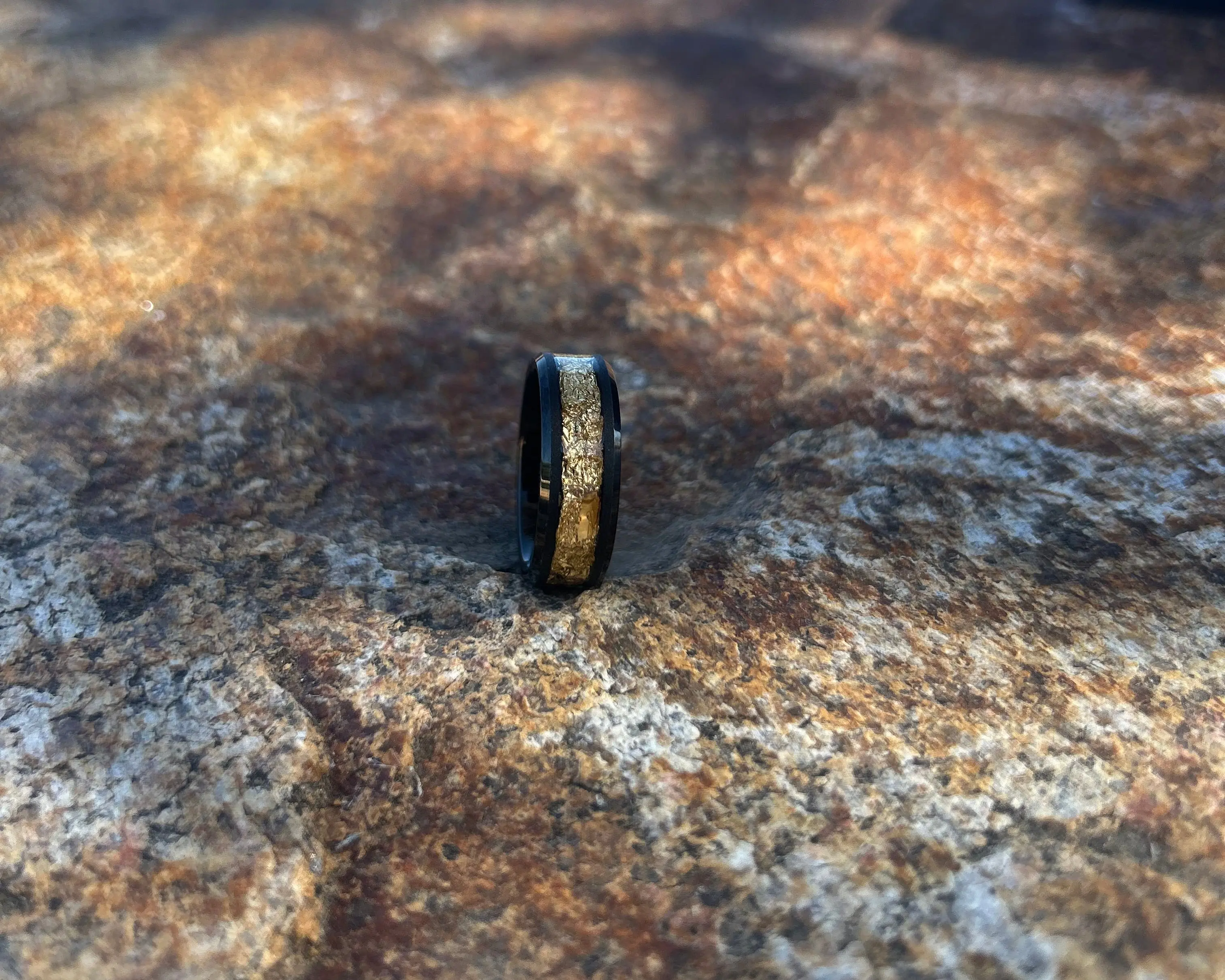 Black ring with gold inlay on a textured stone