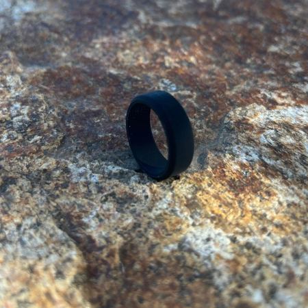 Black silicone ring on a textured stone surface.